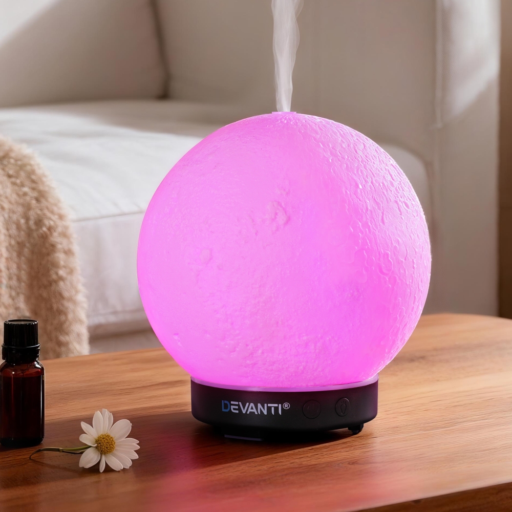 Pink glowing essential oil diffuser on wooden table