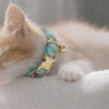 Close-up of kitten wearing floral collar with bell