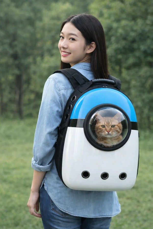 image 1 Woman carrying cat in bubble backpack outdoors