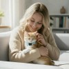 Woman cuddling ginger kitten on sofa