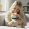 Woman cuddling ginger kitten on sofa