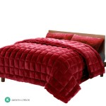 Red quilted king size bedspread on wooden bed