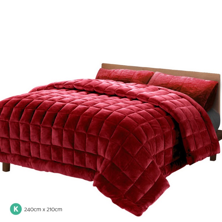 Red quilted king size bedspread on wooden bed