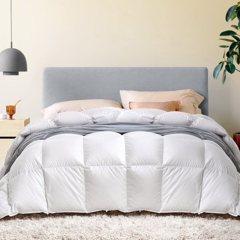 Neatly made bed with white quilt and grey throw