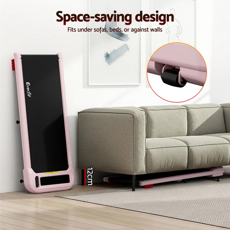 Foldable treadmill stored upright beside sofa