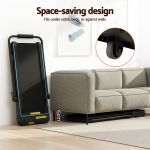 Foldable treadmill stored upright beside sofa