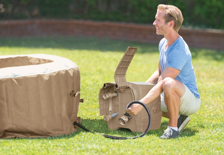 Man inflating outdoor spa with electric pump