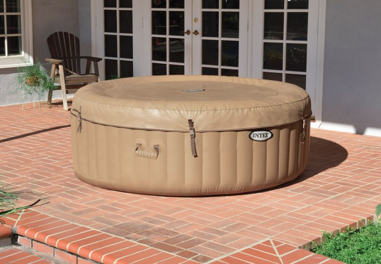 Inflatable outdoor spa with cover on brick patio