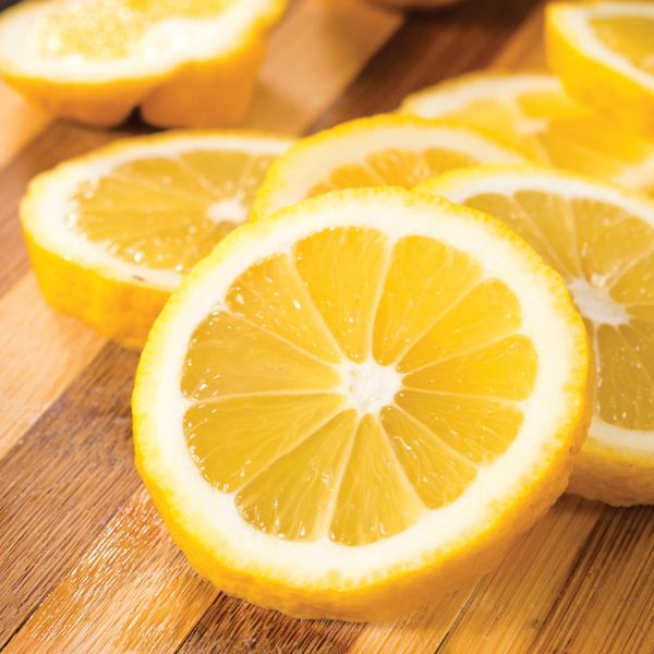 lemon essential oil Fresh lemon slices on wooden cutting board