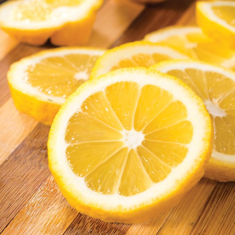 lemon essential oil Fresh lemon slices on wooden cutting board