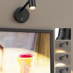 Adjustable black wall light above framed artwork