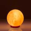 Glowing spherical salt lamp on red base