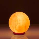 Glowing spherical salt lamp on red base
