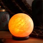 Glowing Himalayan salt lamp on wooden table