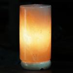 Glowing cylindrical Himalayan salt lamp on dark background
