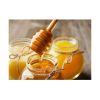 Honey dipper dripping into glass jar of honey