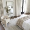 Minimalist bedroom with mirror, armchair and knitted throw