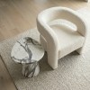 Cream boucle armchair beside marble side table