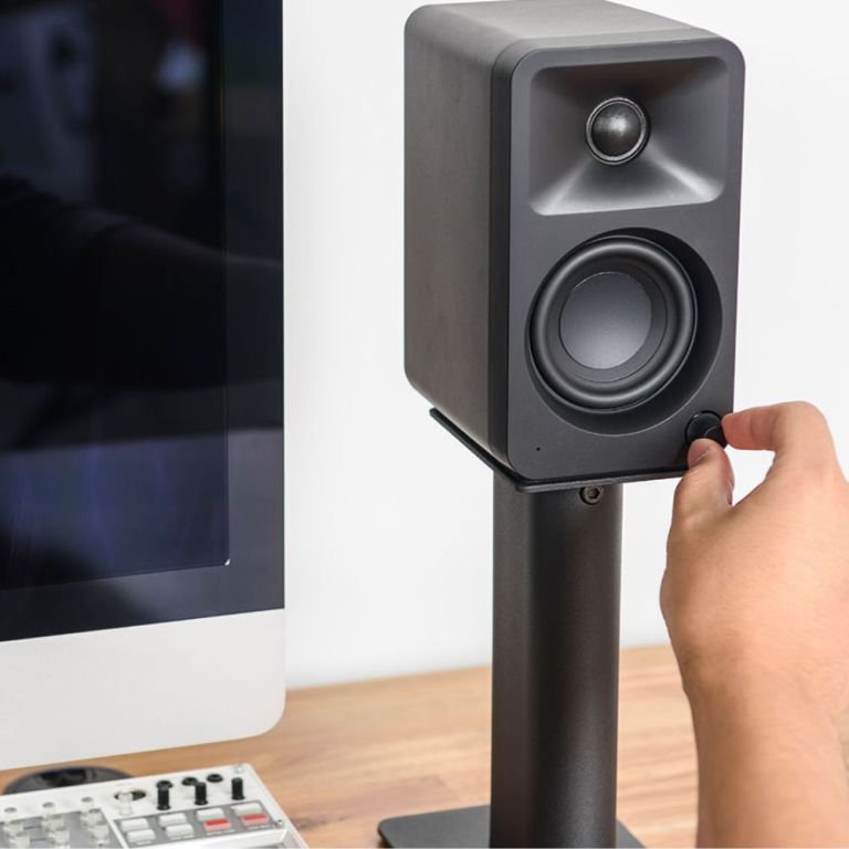 Hand adjusting volume on desktop speaker