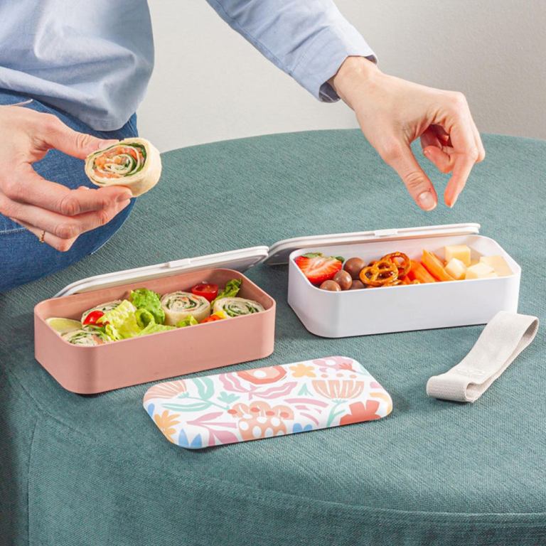 Open lunchboxes with wraps, fruit and snacks