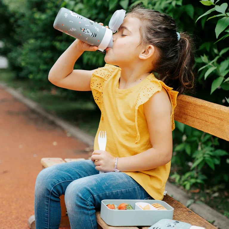 monbento mb pop insulated bottle raccoon Young girl drinking from bottle on park bench