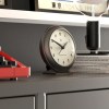 Modern analog clock on shelf with books