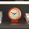 Orange analogue alarm clock on shelf