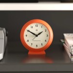 Orange analogue alarm clock on shelf