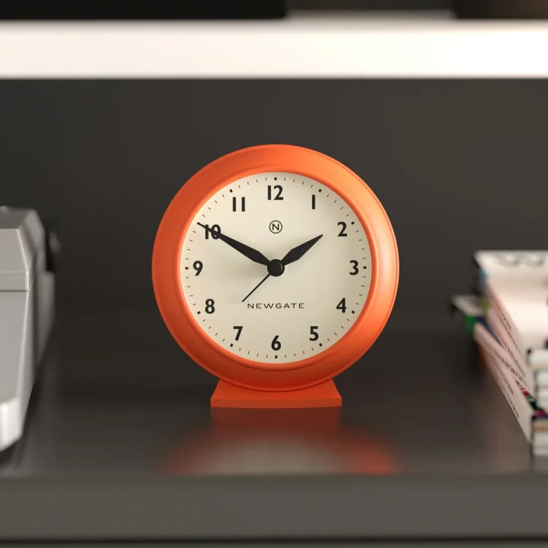 Orange analogue alarm clock on shelf