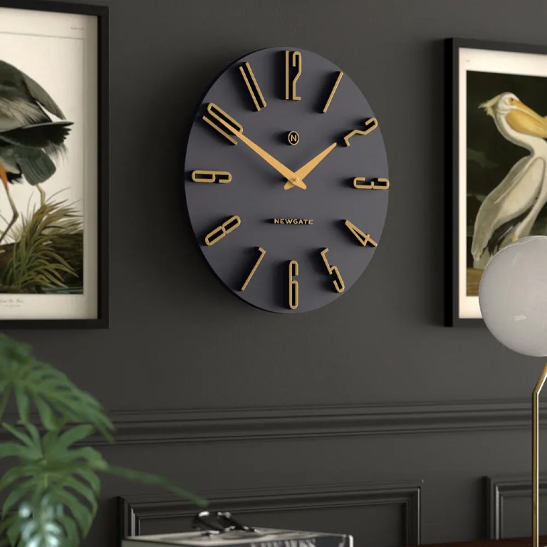 Modern black and gold wall clock on dark wall