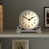 White mantel clock on shelf with books