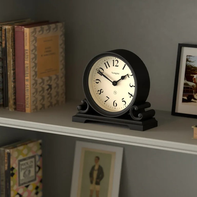 Black mantel clock on shelf with books