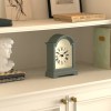 Sage green mantel clock on white shelf