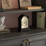 Black mantel clock on grey shelf with books