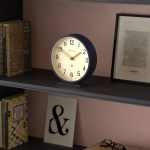Round desk clock on shelf with books