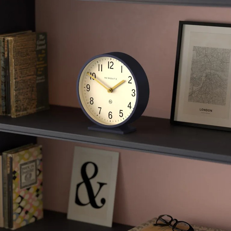 Round desk clock on shelf with books