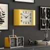 Yellow square wall clock on dark grey wall