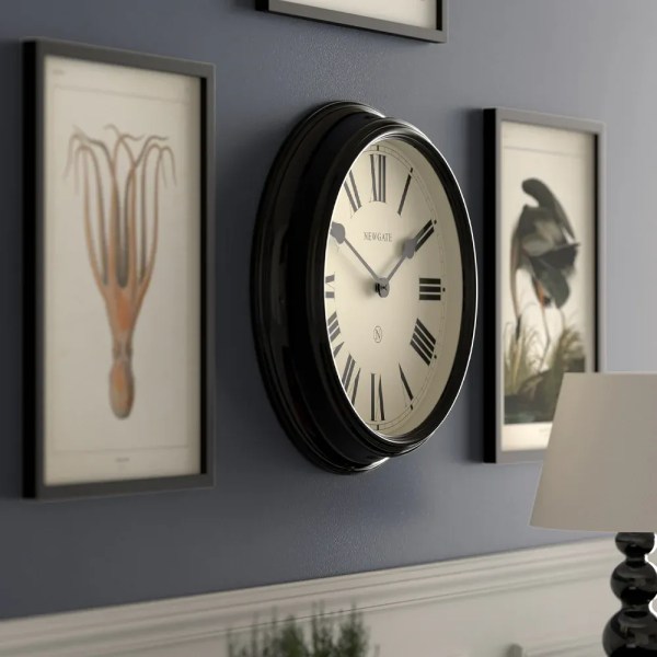 Black Roman numeral wall clock on blue wall
