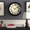 Black Roman numeral wall clock on grey wall
