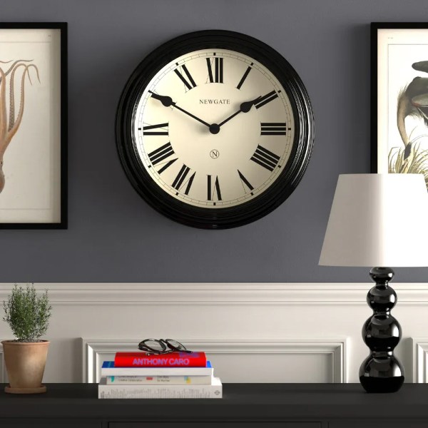 Black Roman numeral wall clock on grey wall