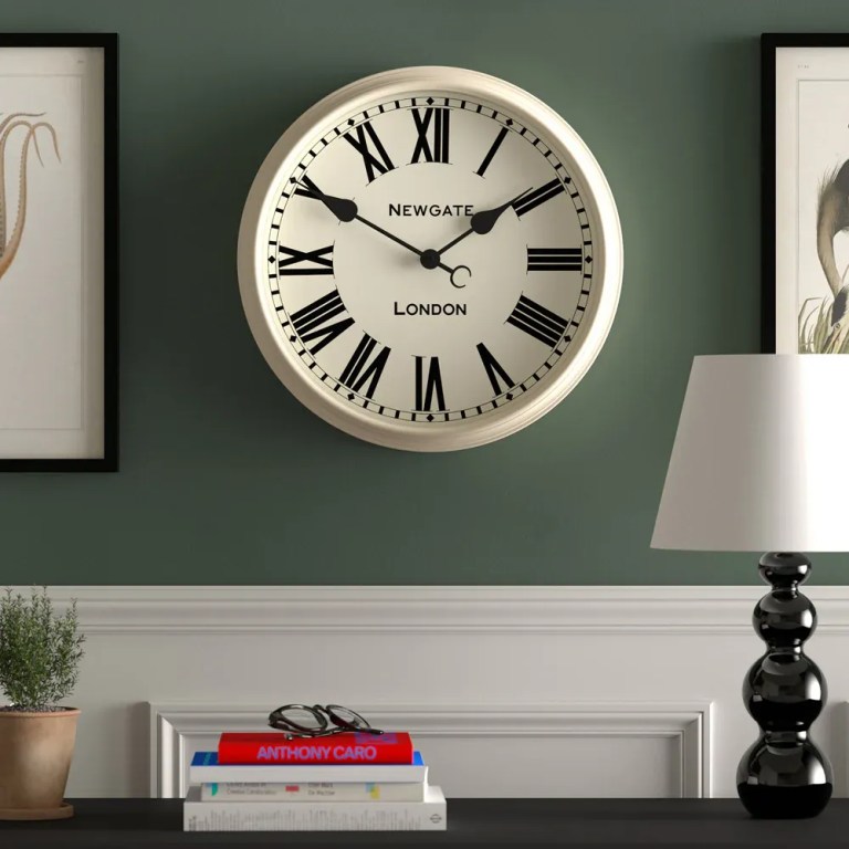 Classic Roman numeral wall clock on green wall