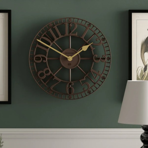 Large vintage metal wall clock on green wall