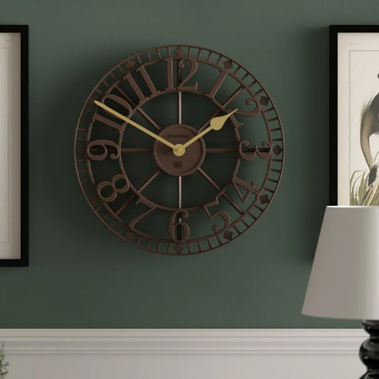 Large vintage metal wall clock on green wall