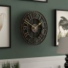 Large black metal wall clock on green wall