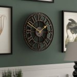 Large black metal wall clock on green wall