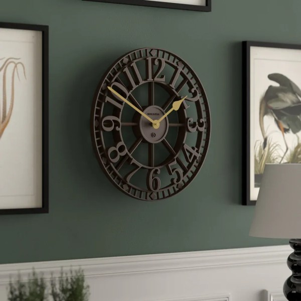 Large black metal wall clock on green wall