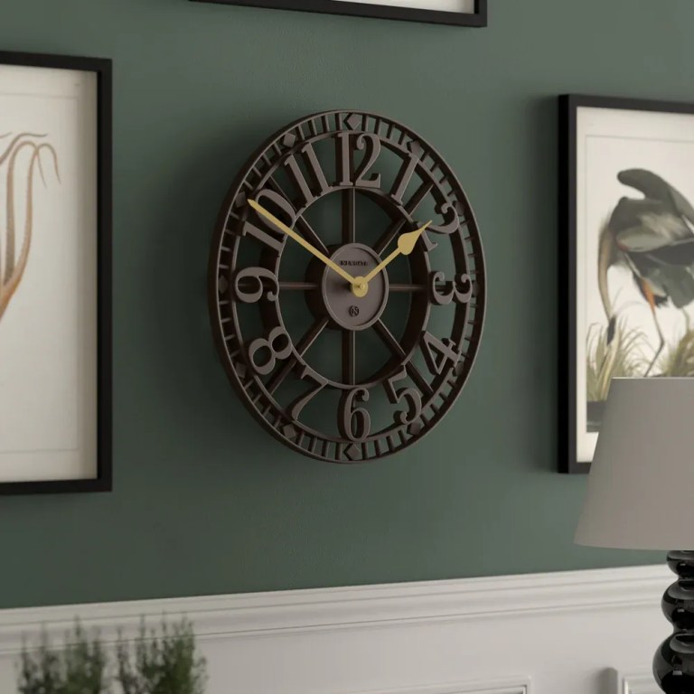 Large black metal wall clock on green wall