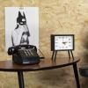 Retro phone and clock beside monochrome poster