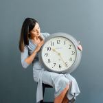 Woman holding large wall clock indoors