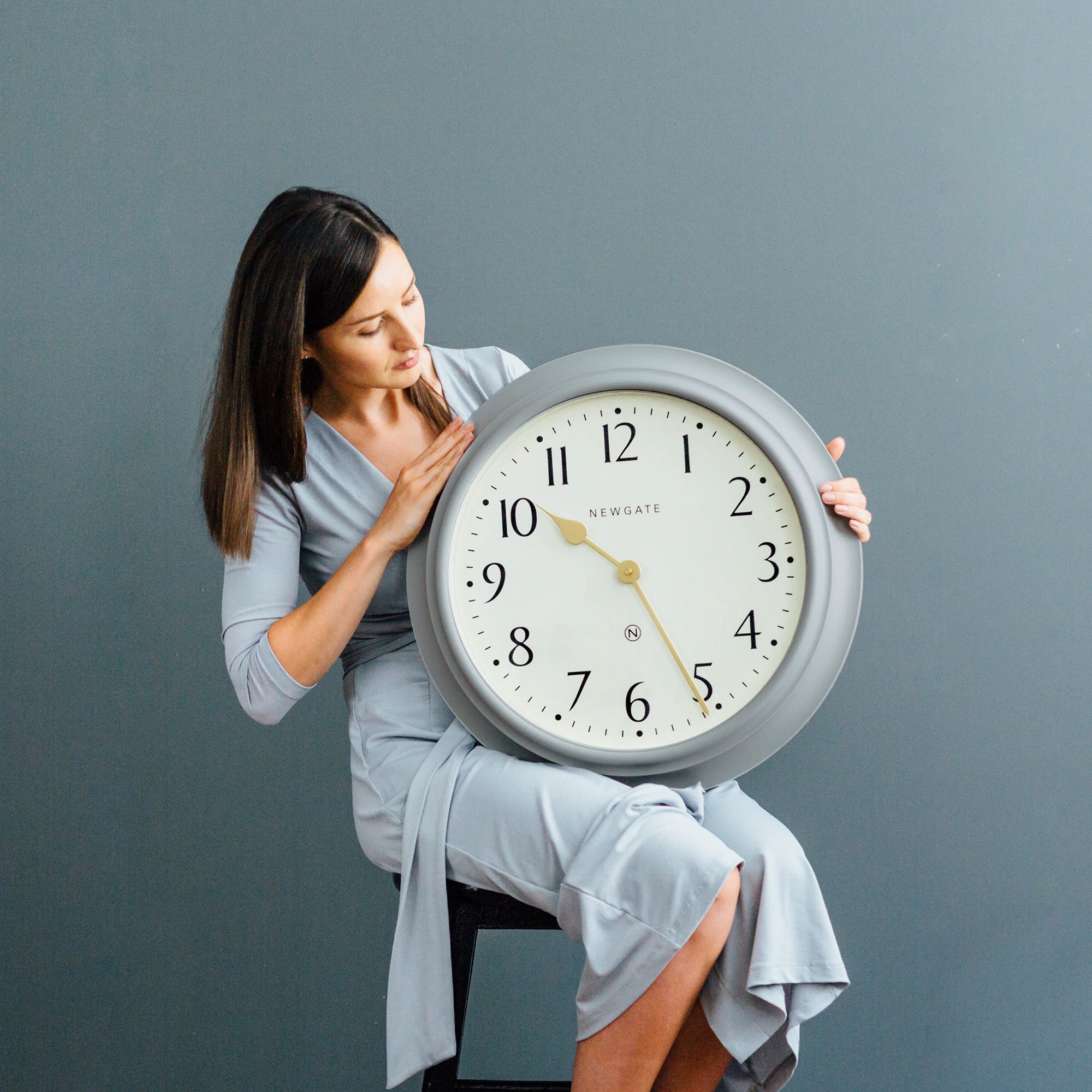 Woman holding large wall clock indoors
